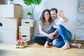 Middle age senior romantic couple in love sitting on the apartment floor with cardboard boxes around and showing house keys Royalty Free Stock Photo