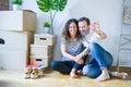 Middle age senior romantic couple in love sitting on the apartment floor with cardboard boxes around and showing house keys Royalty Free Stock Photo