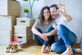 Middle age senior romantic couple in love sitting on the apartment floor with cardboard boxes around and showing house keys Royalty Free Stock Photo