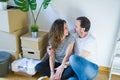 Middle age senior romantic couple in love sitting on the apartment floor with cardboard boxes around and smiling happy for moving Royalty Free Stock Photo