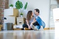 Middle age senior romantic couple in love sitting on the apartment floor with cardboard boxes around and smiling happy for moving Royalty Free Stock Photo