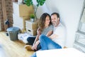 Middle age senior romantic couple in love sitting on the apartment floor with cardboard boxes around and smiling happy for moving Royalty Free Stock Photo