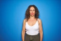 Middle age senior woman with curly hair standing over blue isolated background Relaxed with serious expression on face Royalty Free Stock Photo
