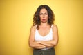 Middle age senior woman with curly hair standing over yellow isolated background skeptic and nervous, disapproving expression on Royalty Free Stock Photo