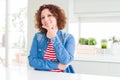 Middle age senior woman with curly hair wearing denim jacket at home looking confident at the camera smiling with crossed arms and Royalty Free Stock Photo
