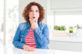 Middle age senior woman with curly hair wearing denim jacket at home Looking fascinated with disbelief, surprise and amazed Royalty Free Stock Photo