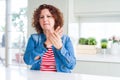 Middle age senior woman with curly hair wearing denim jacket at home Suffering pain on hands and fingers, arthritis inflammation Royalty Free Stock Photo