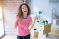 Middle age senior woman moving to a new house packing cardboard boxes very happy and excited doing winner gesture with arms Royalty Free Stock Photo