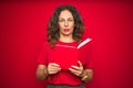 Middle age senior woman reading a book over red isolated background with a confident expression on smart face thinking serious Royalty Free Stock Photo