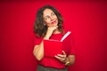 Middle age senior woman reading a book over red isolated background serious face thinking about question, very confused idea Royalty Free Stock Photo