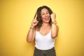 Middle age senior woman showing wrist watch over yellow isolated background surprised with an idea or question pointing finger Royalty Free Stock Photo