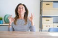 Middle age senior woman sitting at the table at home relaxed and smiling with eyes closed doing meditation gesture with fingers Royalty Free Stock Photo