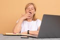 Middle age senior woman sitting at the table at home working using computer laptop bored yawning tired covering mouth Royalty Free Stock Photo