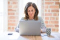 Middle age senior woman sitting at the table at home working using computer laptop with a confident expression on smart face Royalty Free Stock Photo