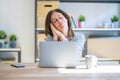 Middle age senior woman sitting at the table at home working using computer laptop sleeping tired dreaming and posing with hands Royalty Free Stock Photo