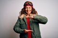 Middle age skier woman wearing snow sportswear and ski goggles over white background gesturing with hands showing big and large