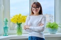 Middle age smiling woman looking at camera, near window at home Royalty Free Stock Photo