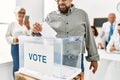 Middle age voter man smiling happy putting vote in voting box at electoral center