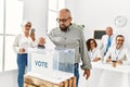 Middle age voter man smiling happy putting vote in voting box at electoral center