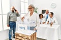 Middle age voter woman smiling happy putting vote in voting box at electoral center