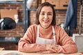 Middle age woman artist smiling confident sitting on table at art studio Royalty Free Stock Photo