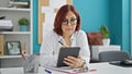 Middle age woman business worker writing on touchpad thinking at the office Royalty Free Stock Photo