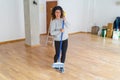 Middle age woman with curly hair working cleaning the house using a broom brush, doing domestic housework chores on new home Royalty Free Stock Photo