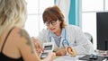 Middle age woman doctor and patient showing ultrasound baby at clinic Royalty Free Stock Photo