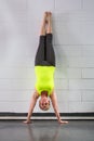 Middle age woman doing handstand across wall