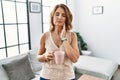 Middle age woman drinking a cup coffee at home touching mouth with hand with painful expression because of toothache or dental Royalty Free Stock Photo