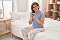 Middle age woman drinking cup of coffee sitting on bed at bedroom Royalty Free Stock Photo