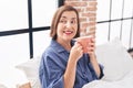 Middle age woman drinking cup of coffee sitting on bed at bedroom Royalty Free Stock Photo