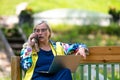 Middle age woman at the garden working from home using laptop and speaking on the phone Royalty Free Stock Photo