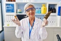 Middle age woman with grey hair doing weed oil extraction at laboratory relaxed with serious expression on face