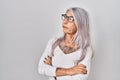 Middle age woman with grey hair standing over white background looking to the side with arms crossed convinced and confident Royalty Free Stock Photo