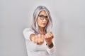 Middle age woman with grey hair standing over white background punching fist to fight, aggressive and angry attack, threat and