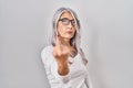 Middle age woman with grey hair standing over white background showing middle finger, impolite and rude fuck off expression