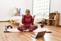 Middle age woman with grey hair training at home looking at exercise video on laptop celebrating mad and crazy for success with Royalty Free Stock Photo