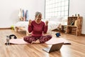 Middle age woman with grey hair training at home looking at exercise video on laptop screaming proud, celebrating victory and Royalty Free Stock Photo