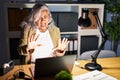 Middle age woman with grey hair working using computer laptop late at night afraid and terrified with fear expression stop gesture Royalty Free Stock Photo