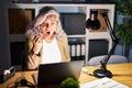 Middle age woman with grey hair working using computer laptop late at night angry and mad raising fist frustrated and furious Royalty Free Stock Photo