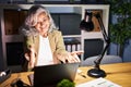 Middle age woman with grey hair working using computer laptop late at night looking at the camera smiling with open arms for hug Royalty Free Stock Photo