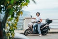 Middle-age woman in helmet and sunglasses on motor scooter on the Sicilian old town streets in the Forza d`Agro with Sant`Alessi