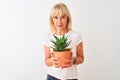 Middle age woman holding cactus pot standing over isolated white background with a confident expression on smart face thinking Royalty Free Stock Photo