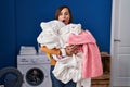 Middle age woman holding dirty laundry ready to put it in the washing machine afraid and shocked with surprise and amazed Royalty Free Stock Photo