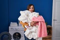 Middle age woman holding dirty laundry ready to put it in the washing machine clueless and confused expression Royalty Free Stock Photo