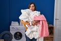 Middle age woman holding dirty laundry ready to put it in the washing machine depressed and worry for distress, crying angry and Royalty Free Stock Photo