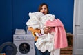 Middle age woman holding dirty laundry ready to put it in the washing machine in shock face, looking skeptical and sarcastic, Royalty Free Stock Photo