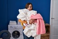 Middle age woman holding dirty laundry ready to put it in the washing machine skeptic and nervous, frowning upset because of Royalty Free Stock Photo