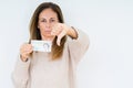 Middle age woman holding 5 pounds bank note over isolated background with angry face, negative sign showing dislike with thumbs